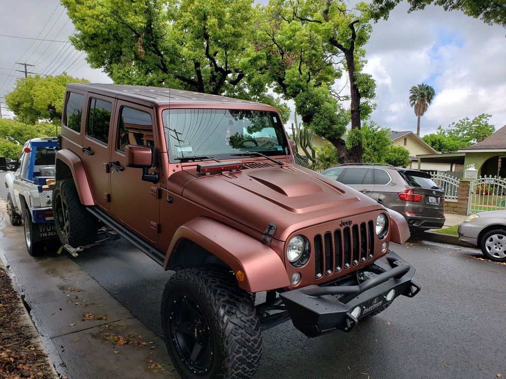 Brown Jeep being towed on a residential street.