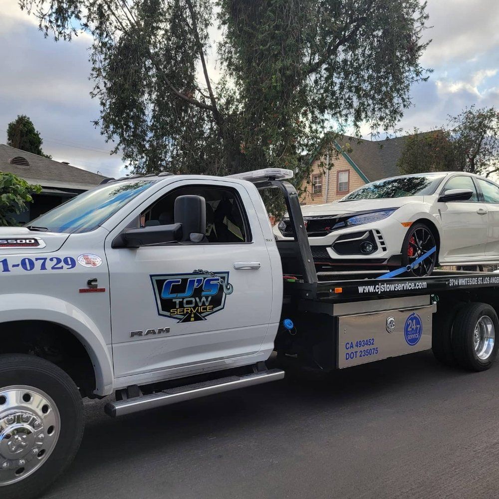 White tow truck carrying a white car on a sunny day.