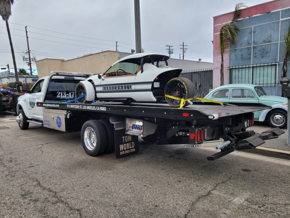 Tow truck hauling a white Ferrari with black rims on a city street.