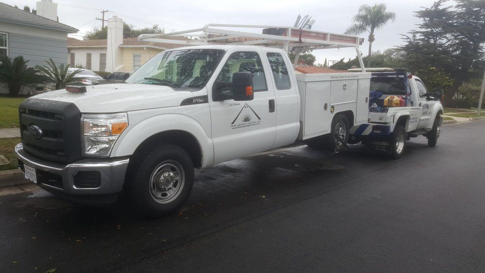 White work truck with ladder rack parked on street in residential area.