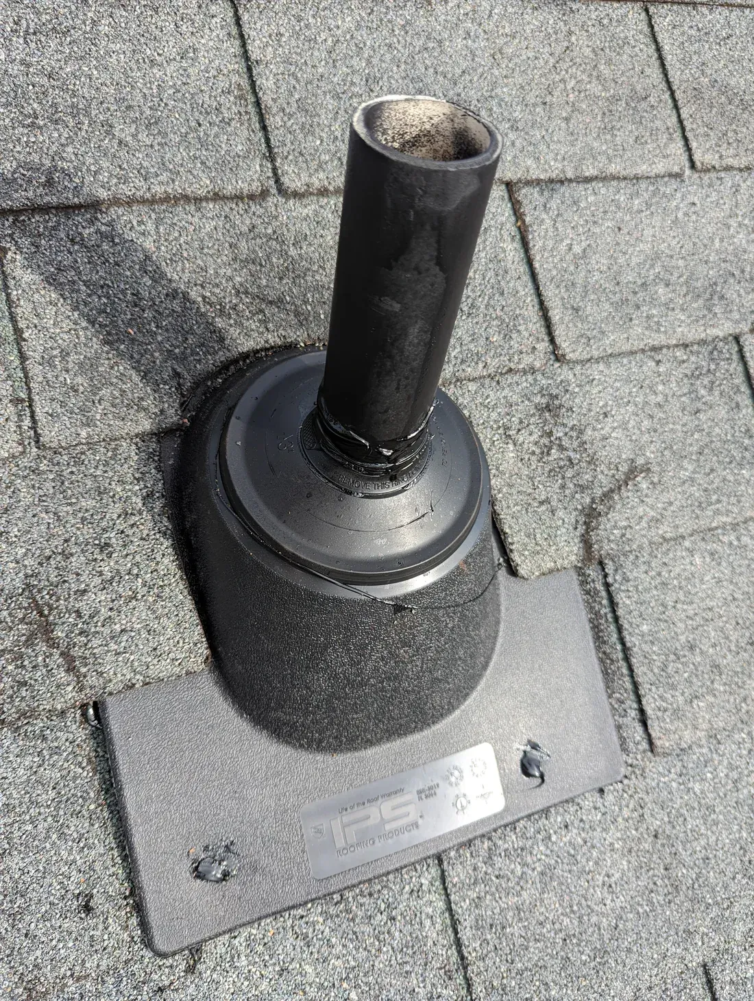 Black pipe flashing on a gray asphalt shingle roof.