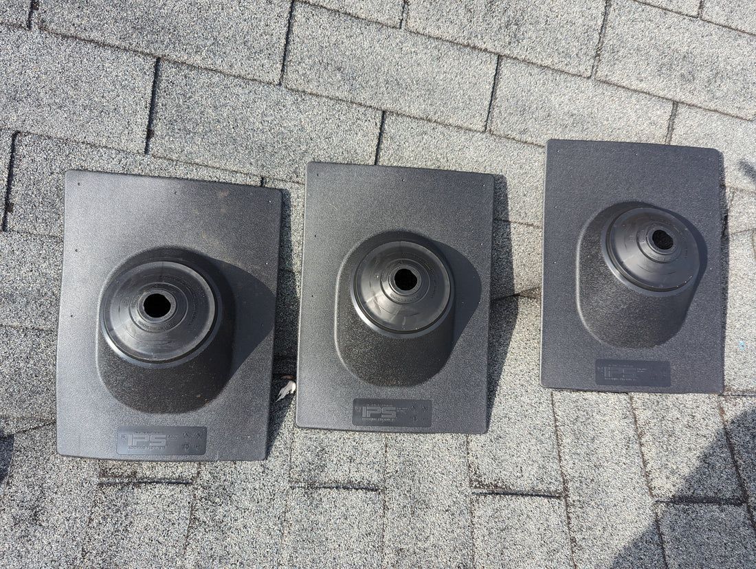 Three black roof pipe flashings on gray asphalt shingles.