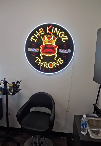 A chair in front of a neon sign that says the kingz throne