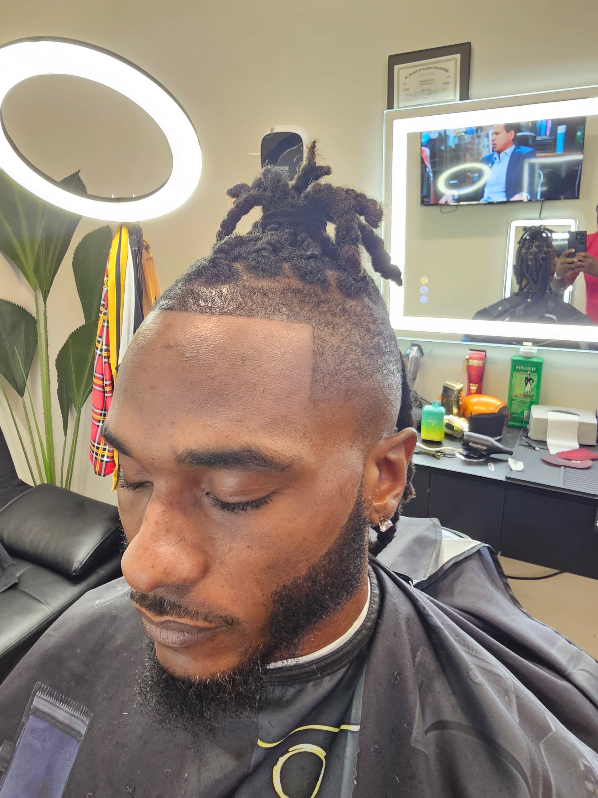 A man is getting his hair cut at a barber shop with a spider in his hair.