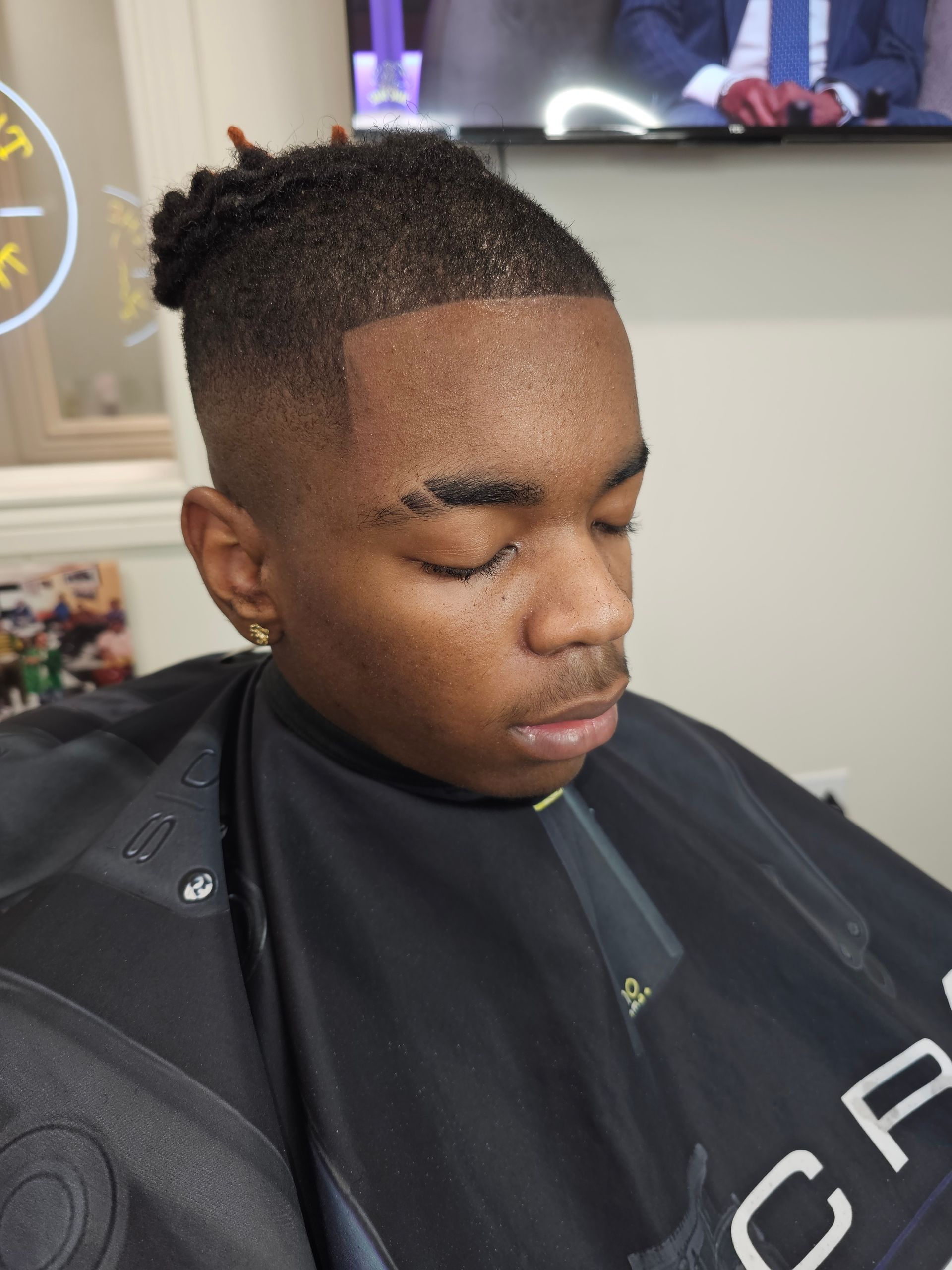 A young man is getting his hair cut at a barber shop