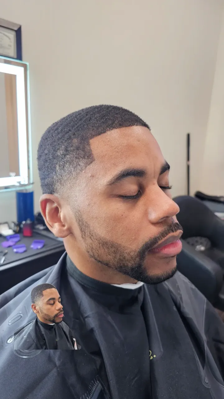 A man with a beard is getting his hair cut at a barber shop.