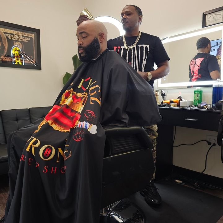 A man is getting his hair cut by a barber in a barber shop.