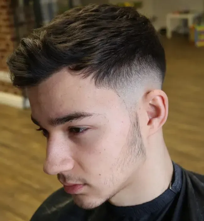 A young man is getting his hair cut at a barber shop.
