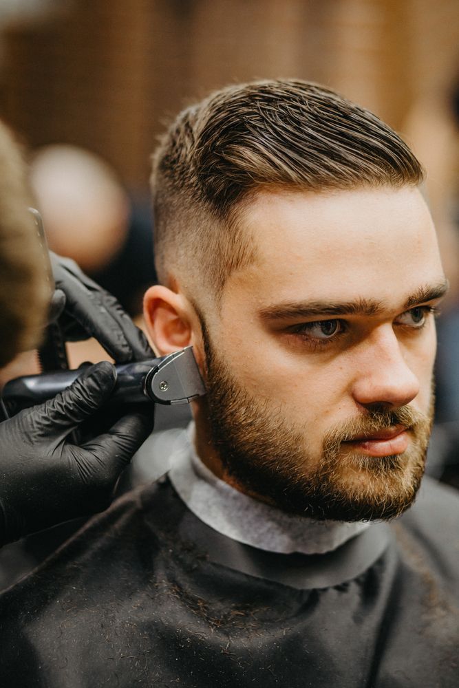 A man is getting his hair cut by a barber in a barber shop.
