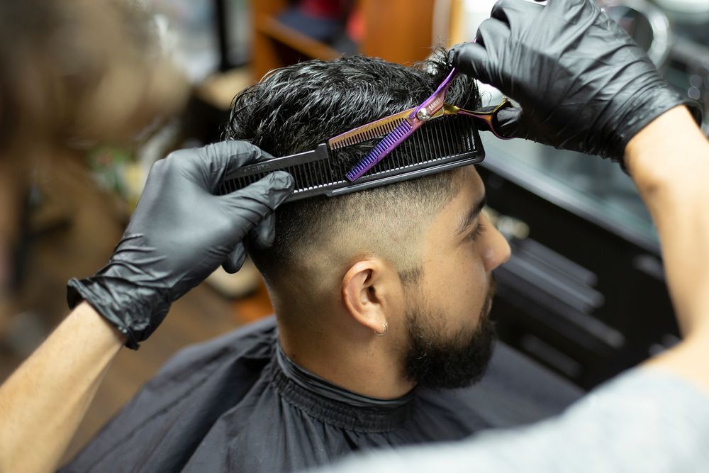 A man is getting his hair cut by a barber in a barber shop.