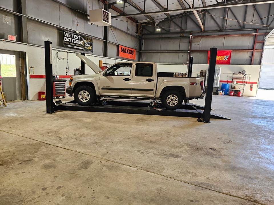 A truck is parked on a lift in a garage.