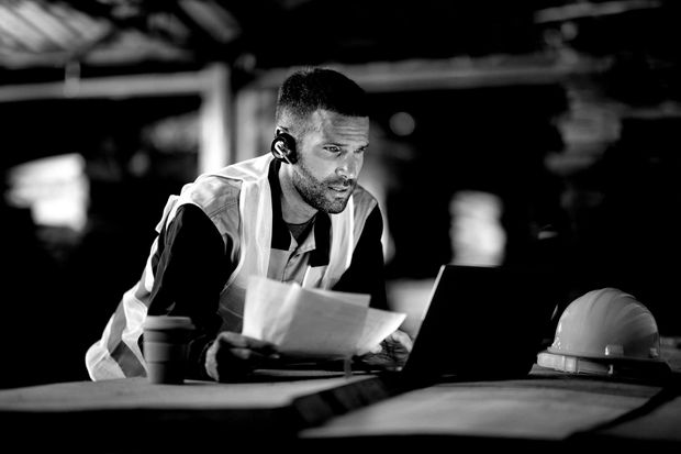 A black and white photo of a man using a laptop computer.