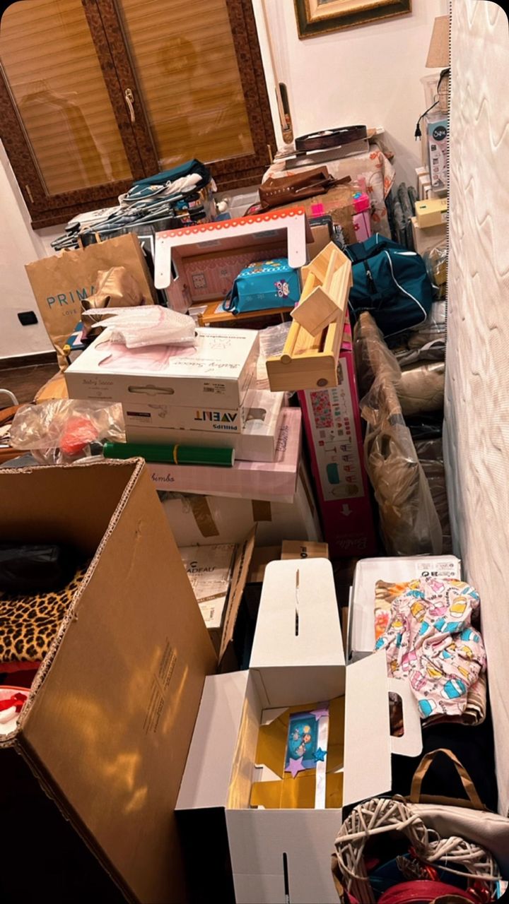 Scatoloni e oggetti ammucchiati in una stanza. Per lo più cartone, con qualche oggetto colorato in vista.