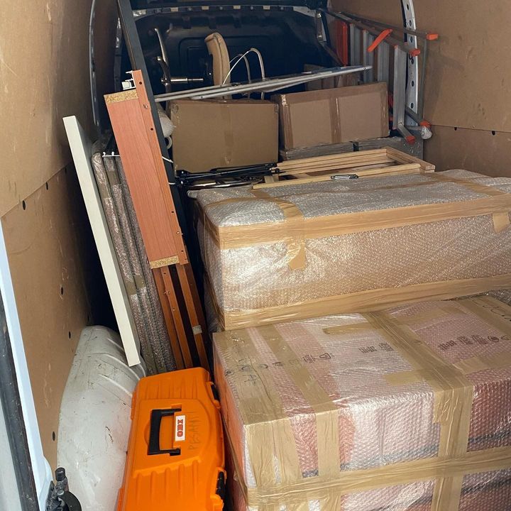 All'interno di un furgone merci, mobili imballati avvolti in pluriball, scatole e una scala.