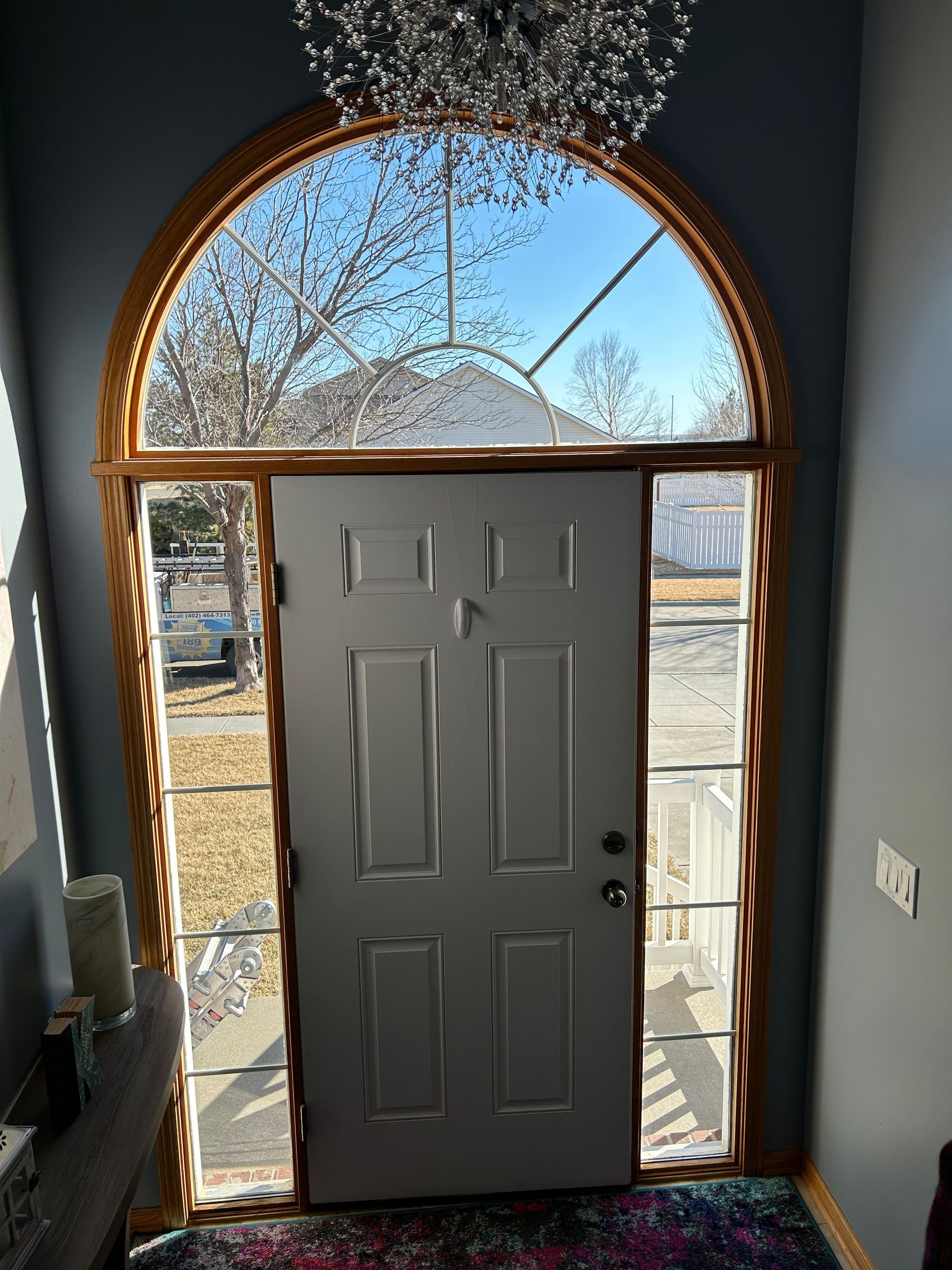 A white door with a stained glass window and a chandelier above it