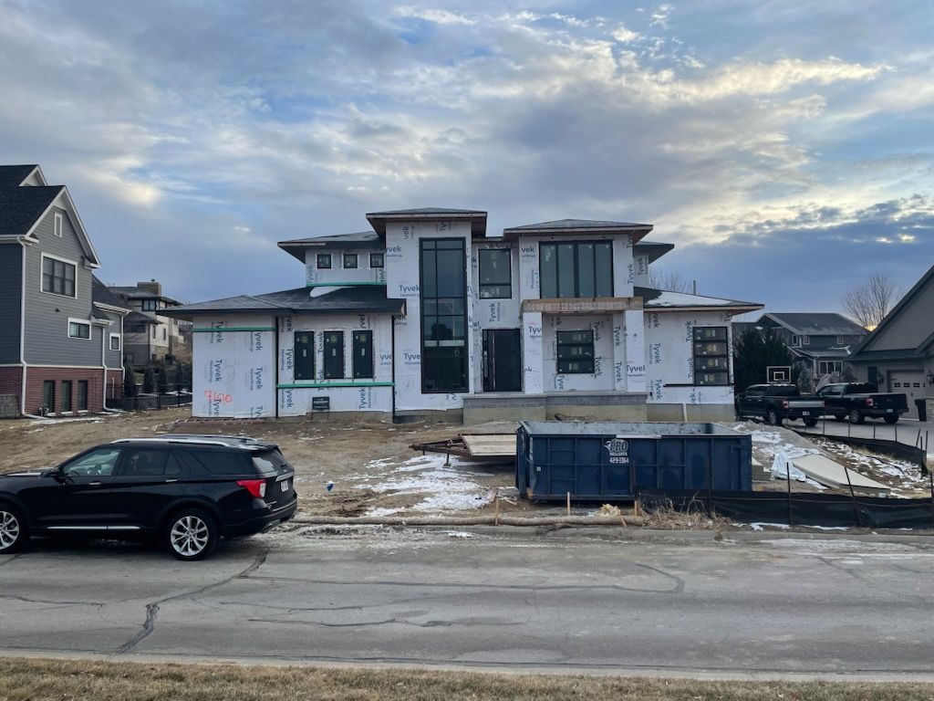A car is parked in front of a house under construction.