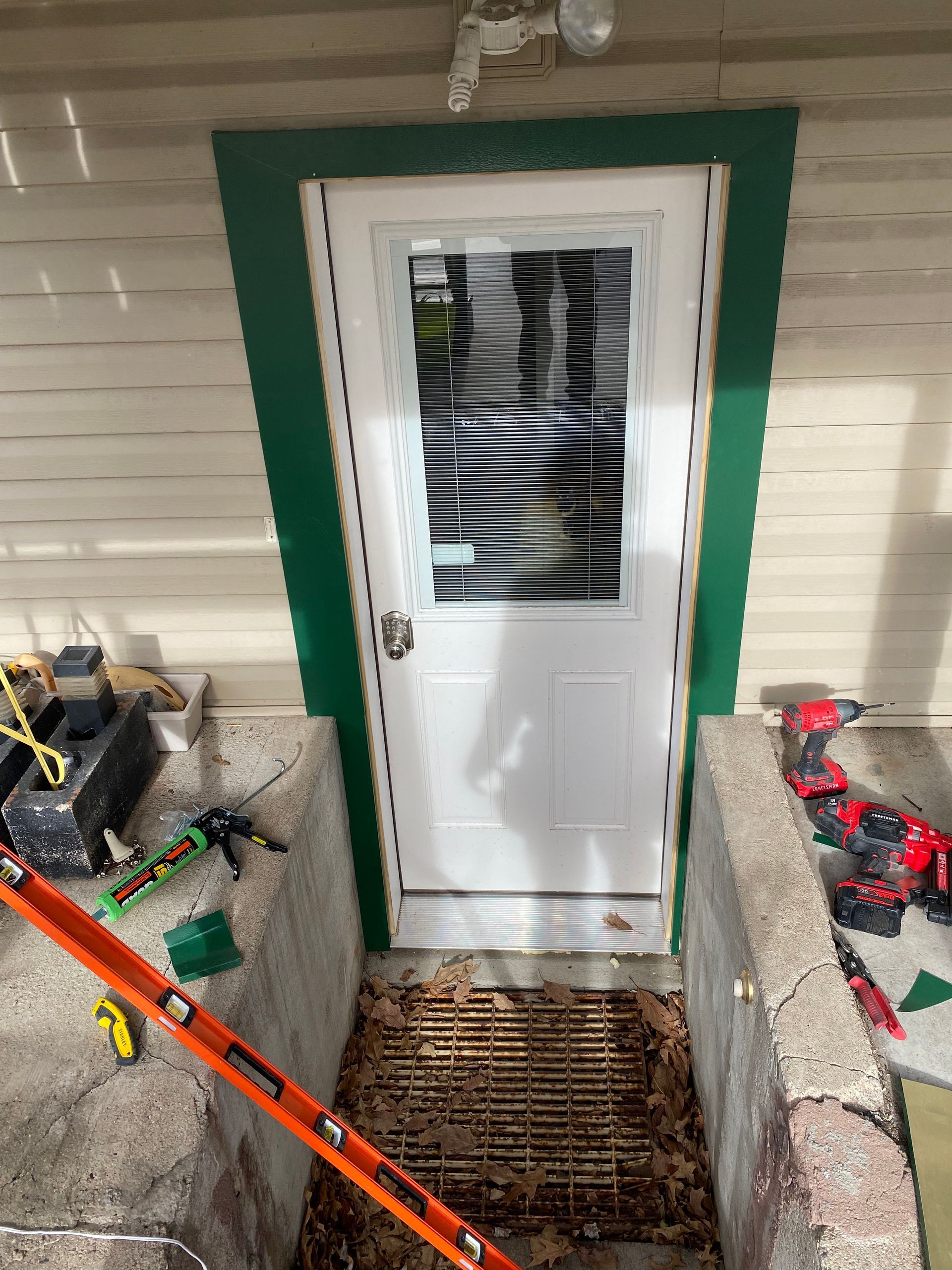 A white door with a green trim is being installed on a house.