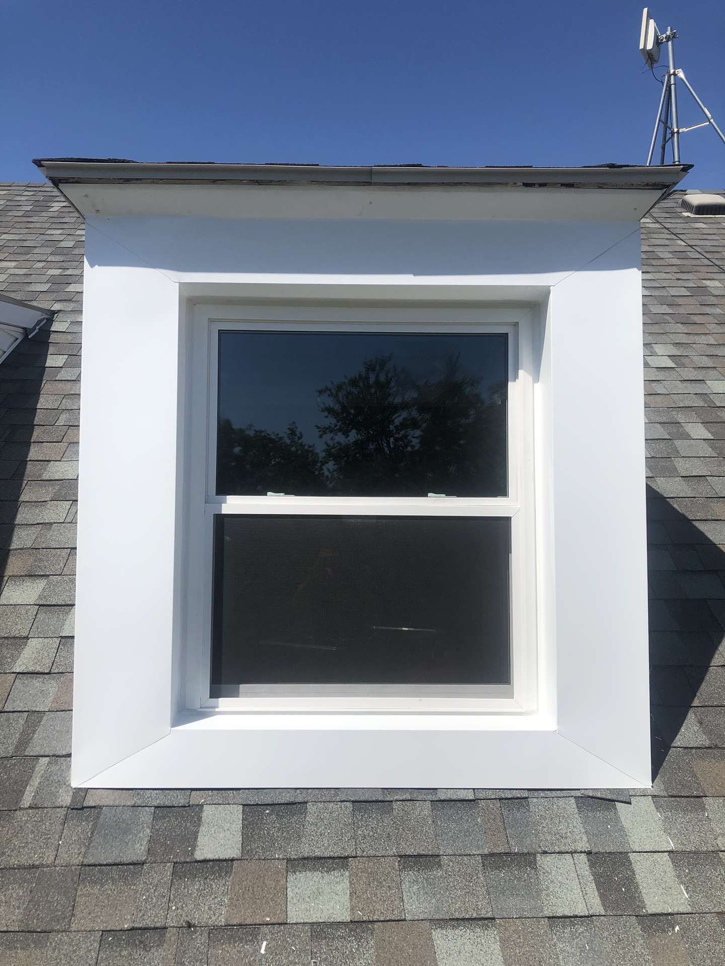 A white window is sitting on top of a roof.