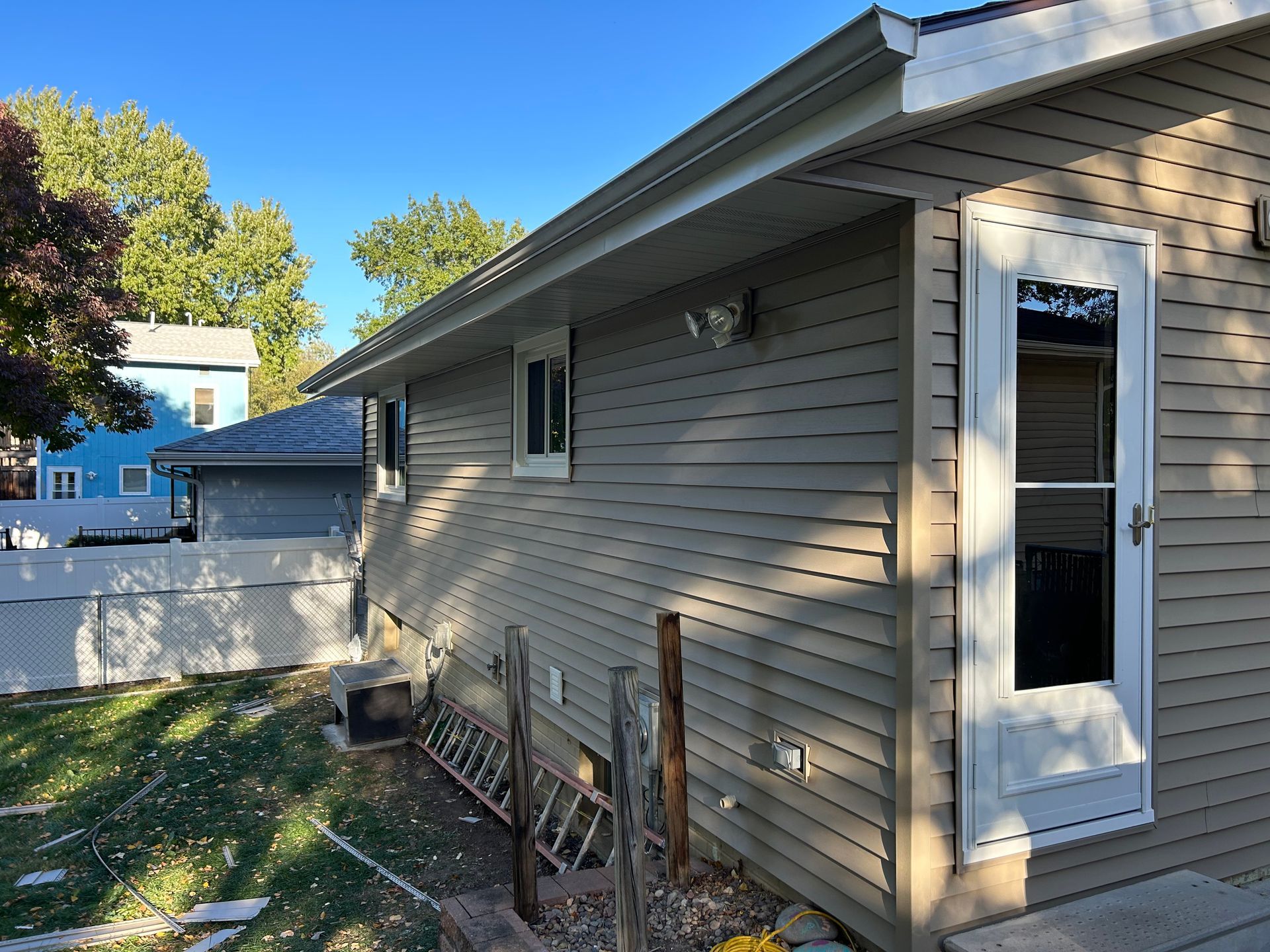 The side of a house with a white door and a white fence.