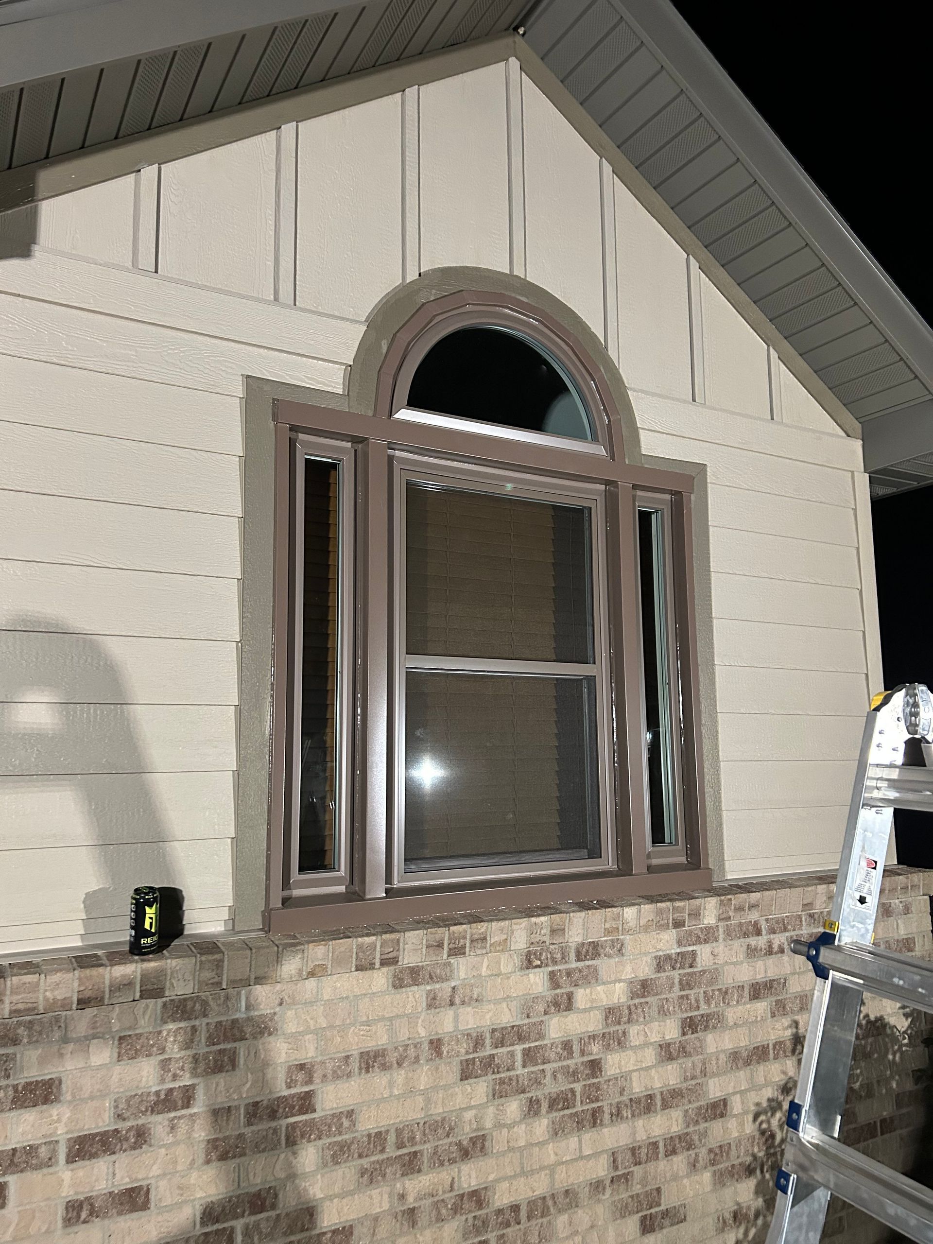A ladder is sitting on the side of a house next to a window.