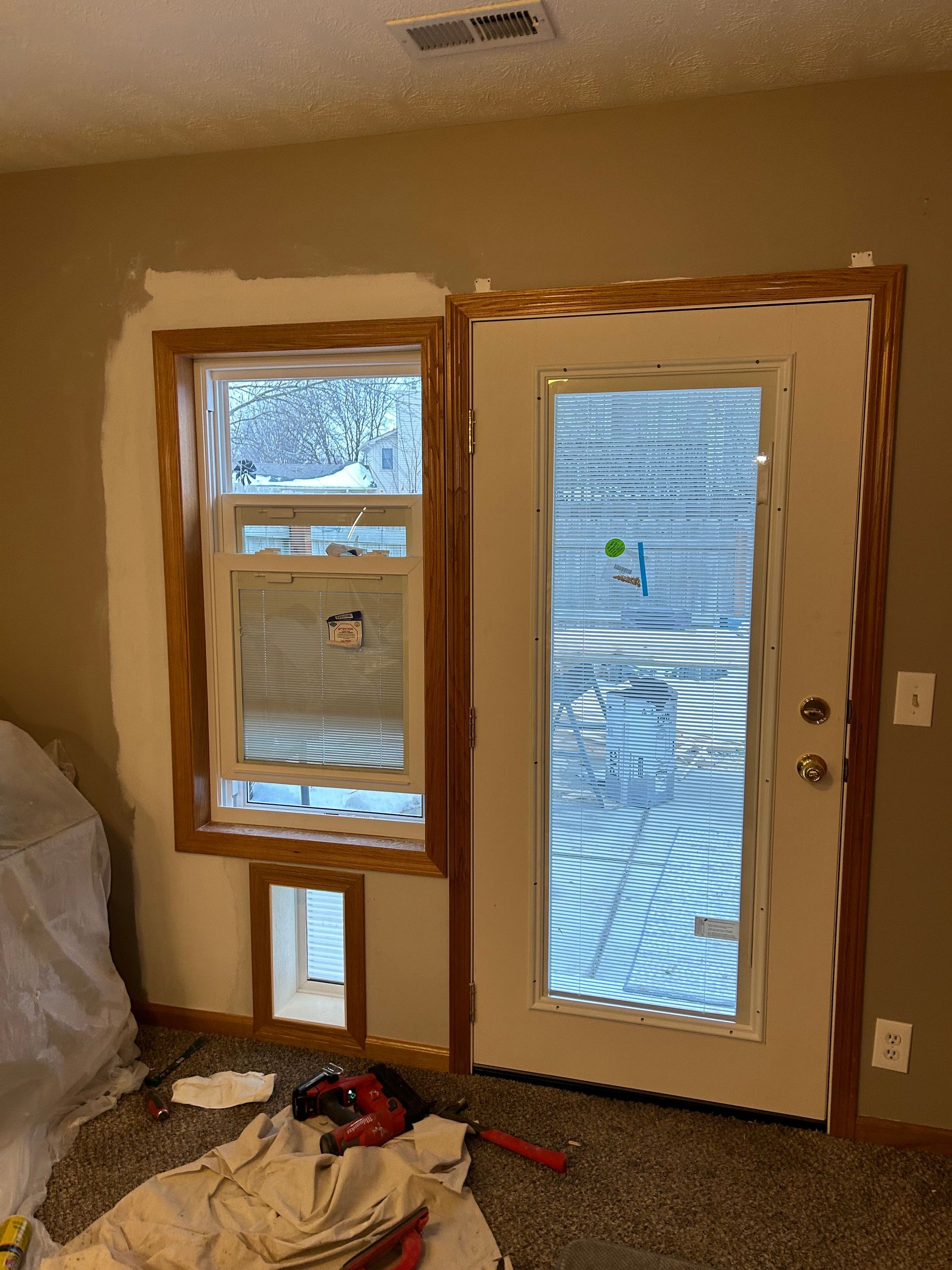 A room with a door and two windows being painted.