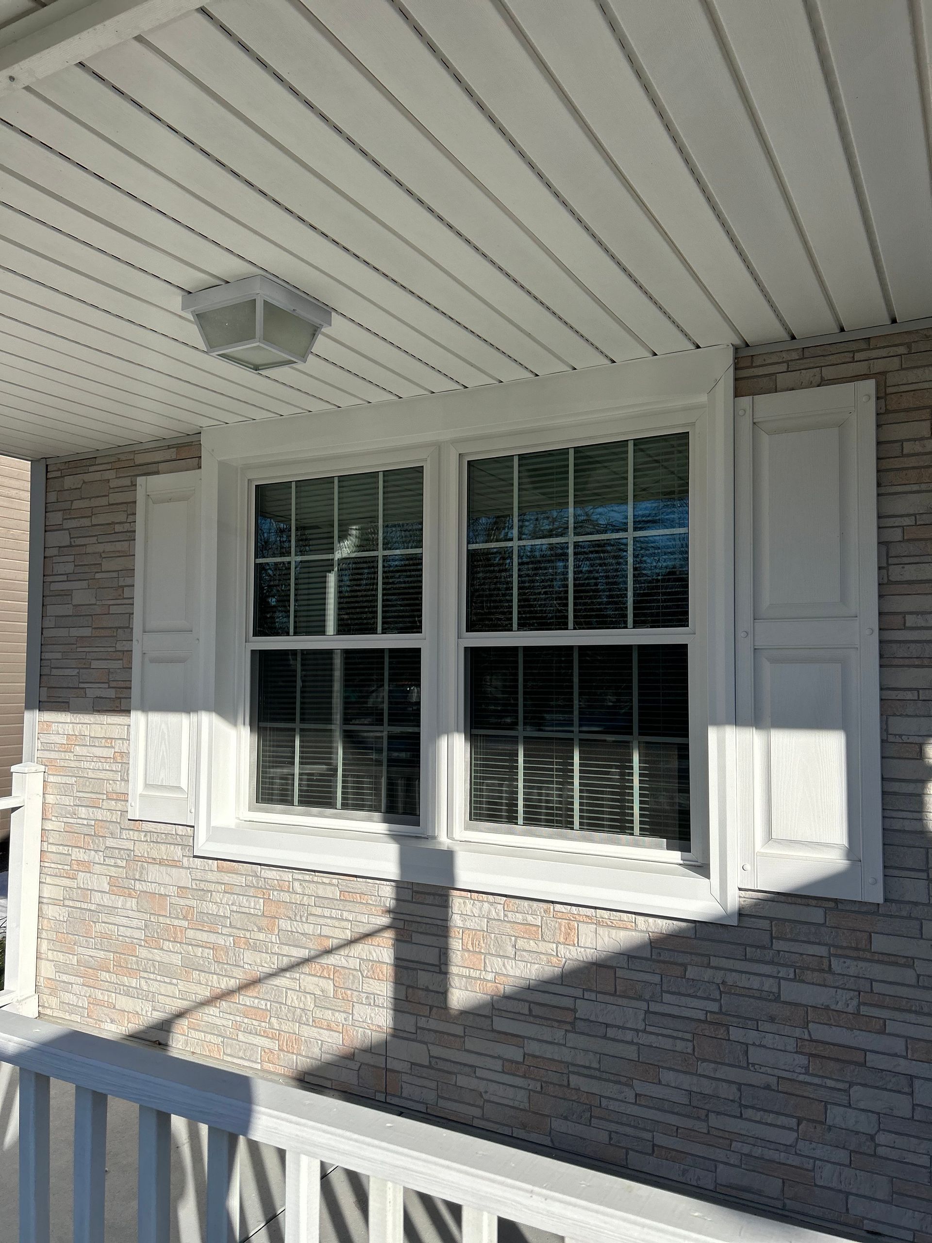 A house with a large window and white shutters on the porch.