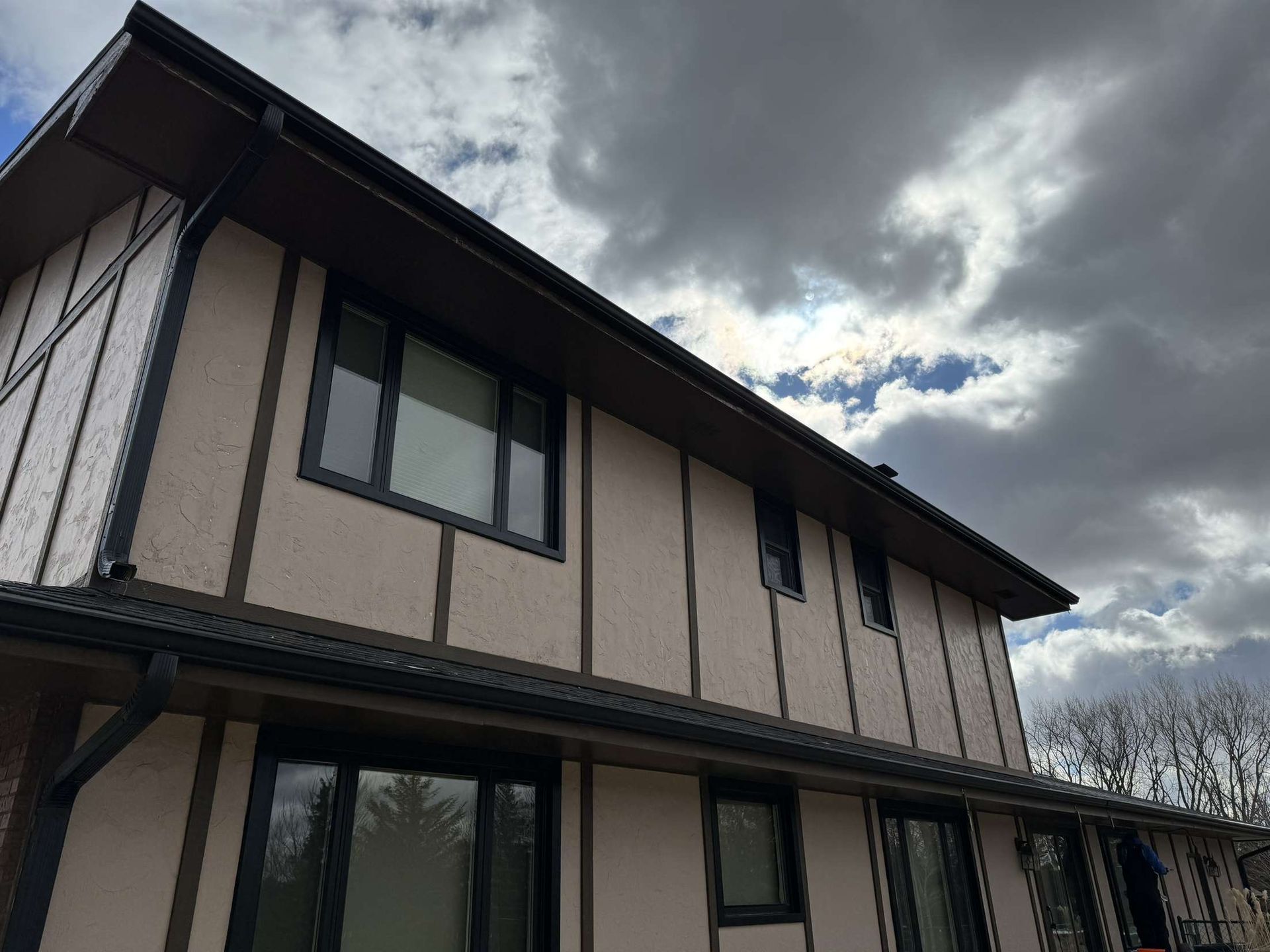 A house with a lot of windows and a cloudy sky in the background