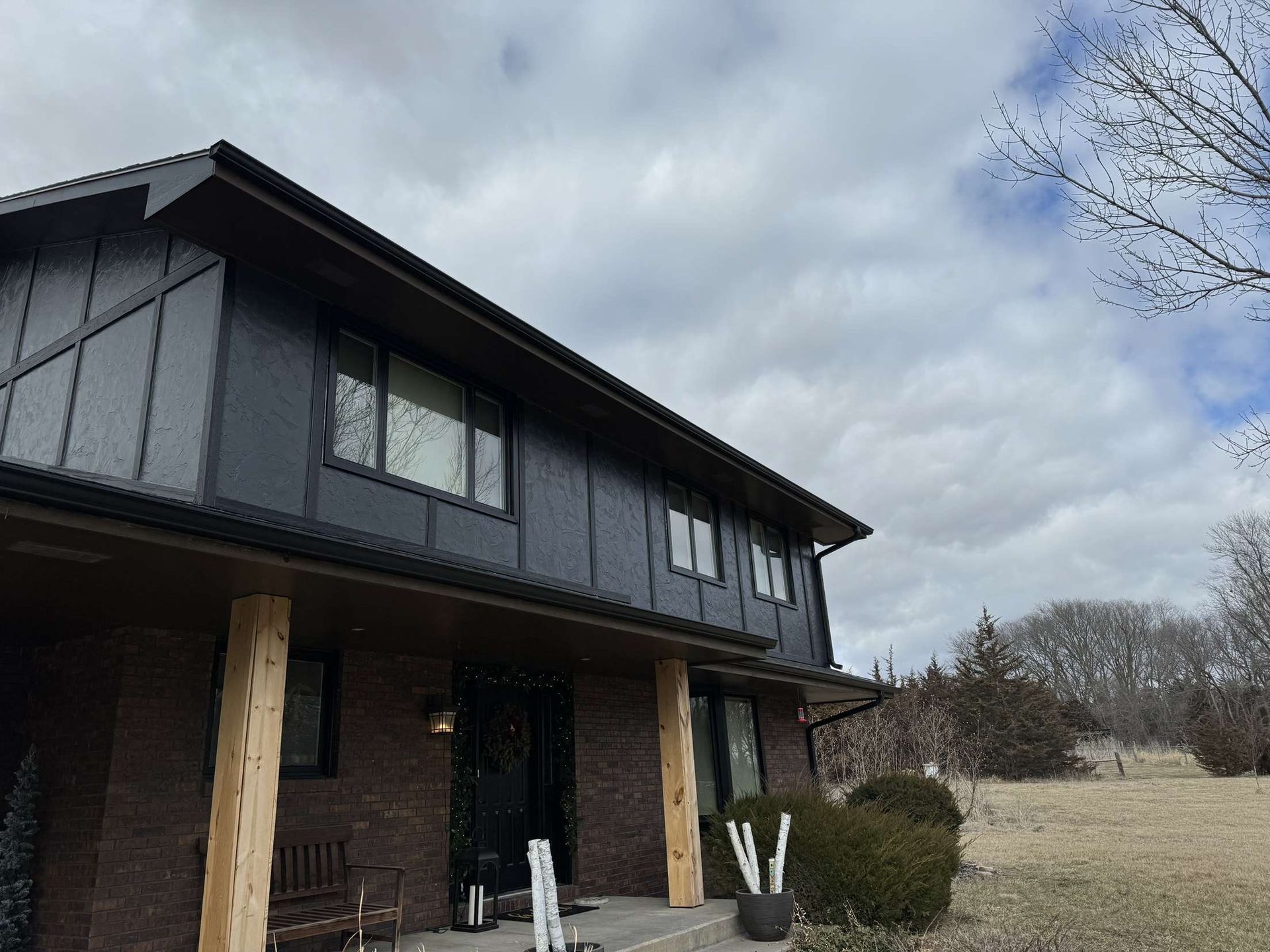 A large house with a lot of windows and a porch on a cloudy day.
