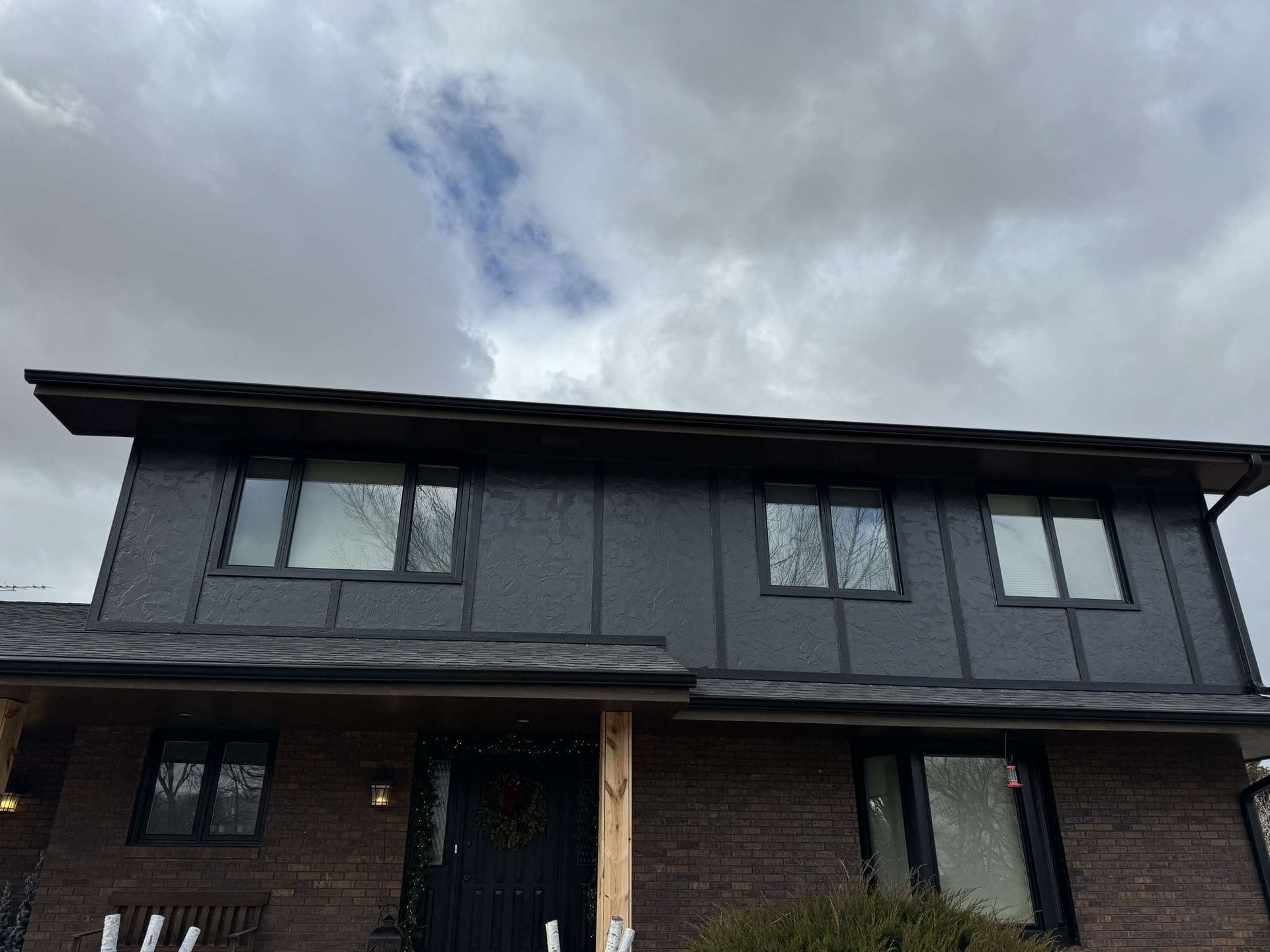 A house with a lot of windows and a cloudy sky in the background.