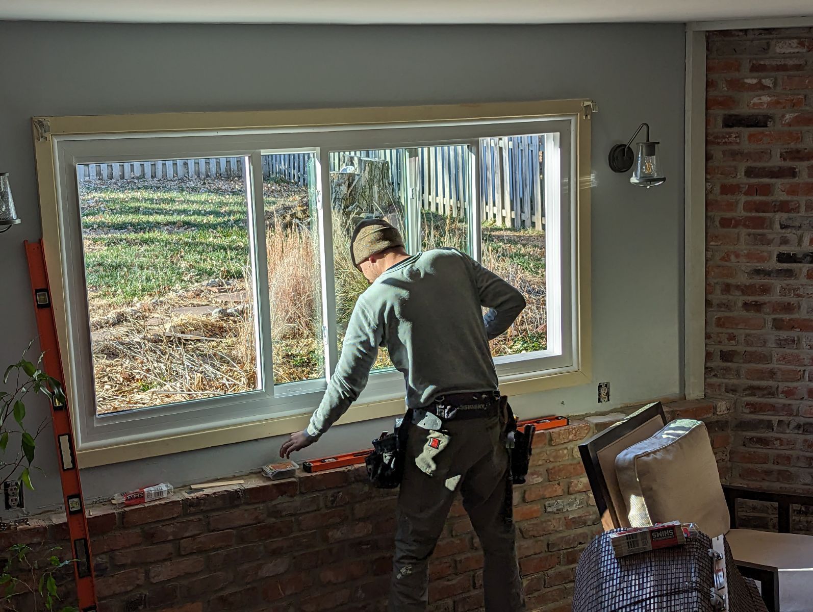 A man is measuring a window in a living room.