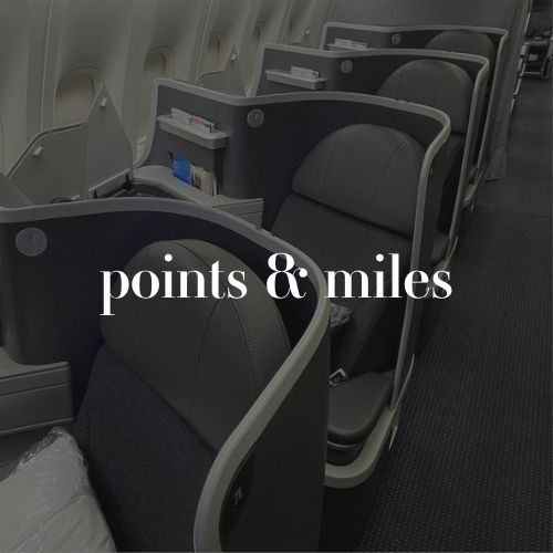Business class airplane seats with dark privacy dividers and a center aisle. White text across the photo reads “points & miles.”