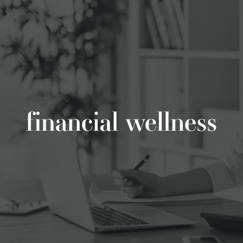 A person writes in a notebook beside an open laptop in a softly blurred office setting. White text across the photo reads “financial wellness.”
