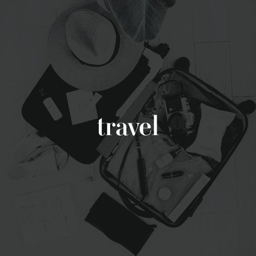 An open suitcase is packed with travel items including a camera. White text across the photo reads “travel.”