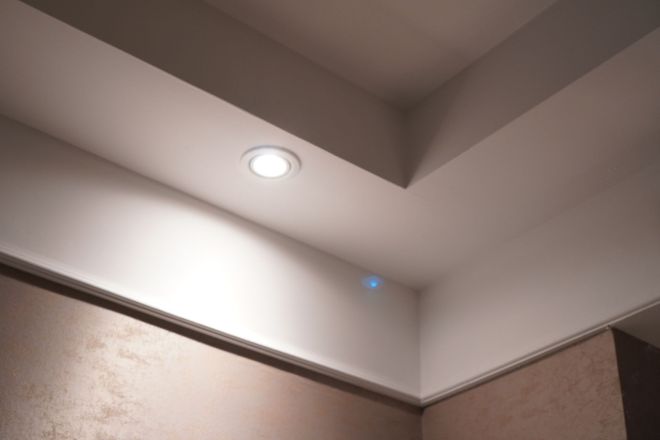 Soffitto bianco con luce da incasso, angolo architettonico e parete marrone.