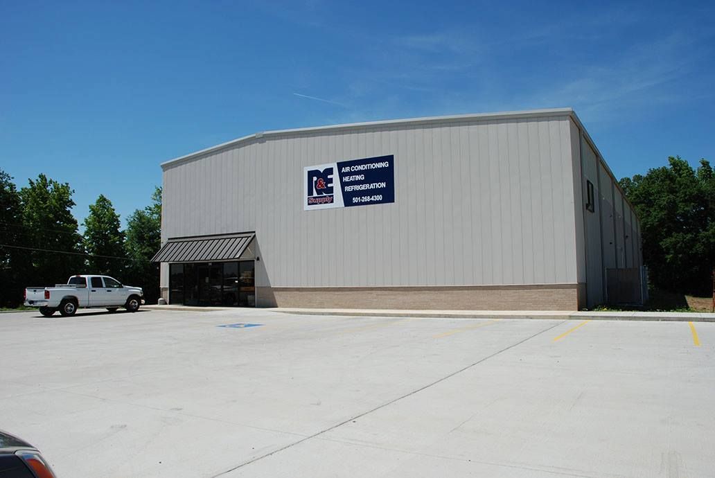 A white truck is parked in front of a large building.