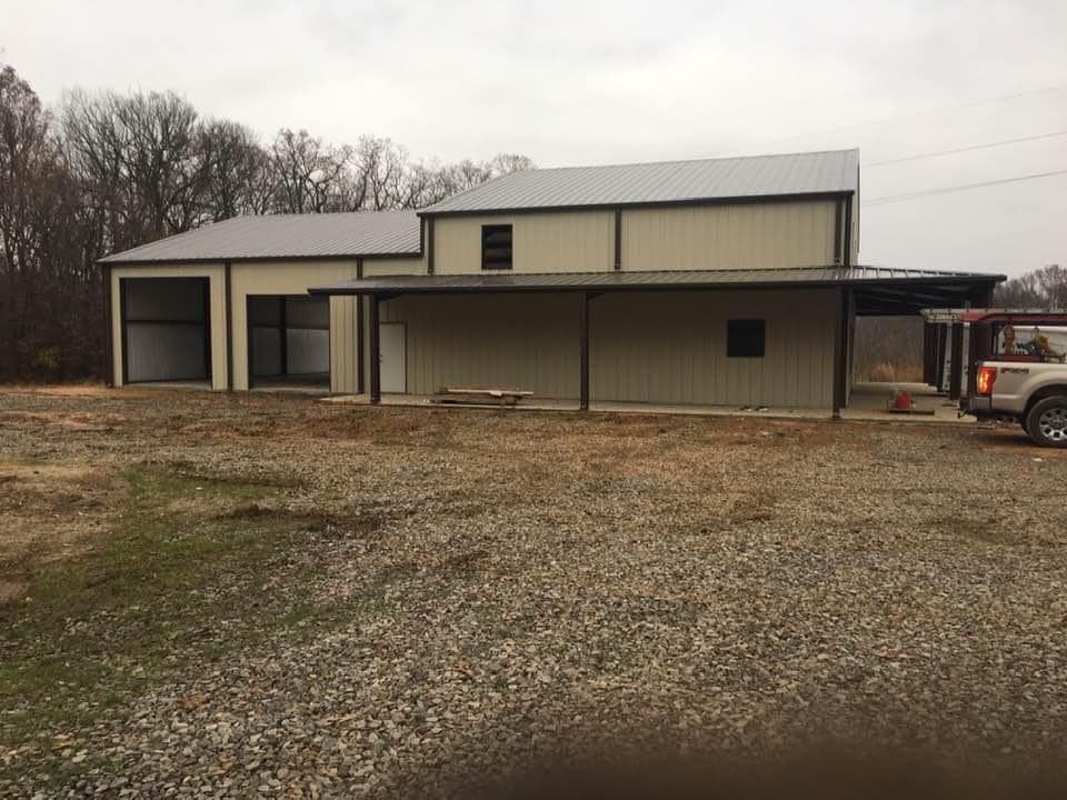 A truck is parked in front of a large metal building.