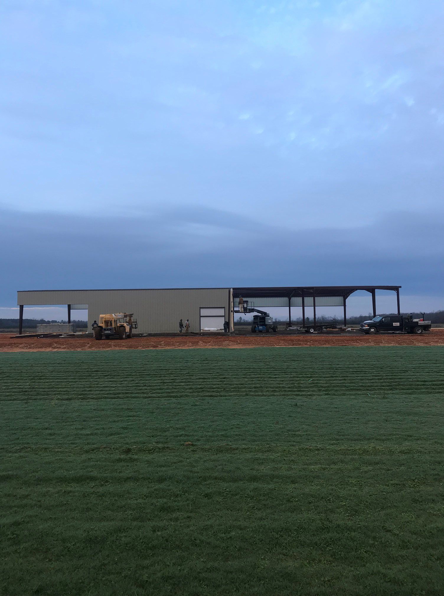A large building is being built in the middle of a field.