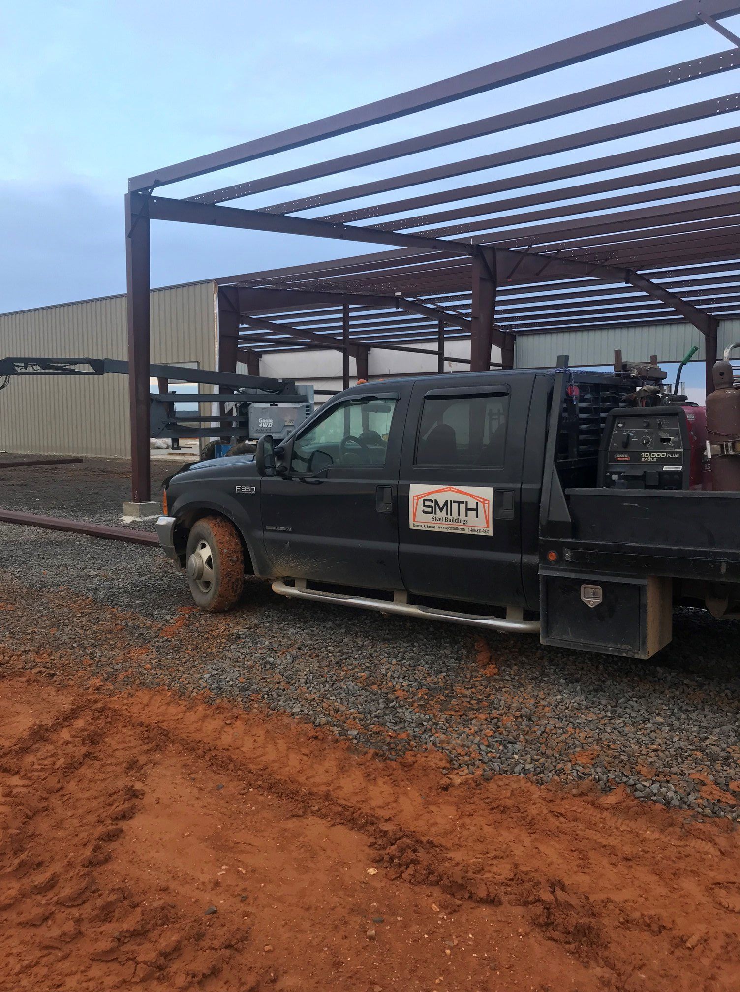 A black truck is parked in front of a building under construction.
