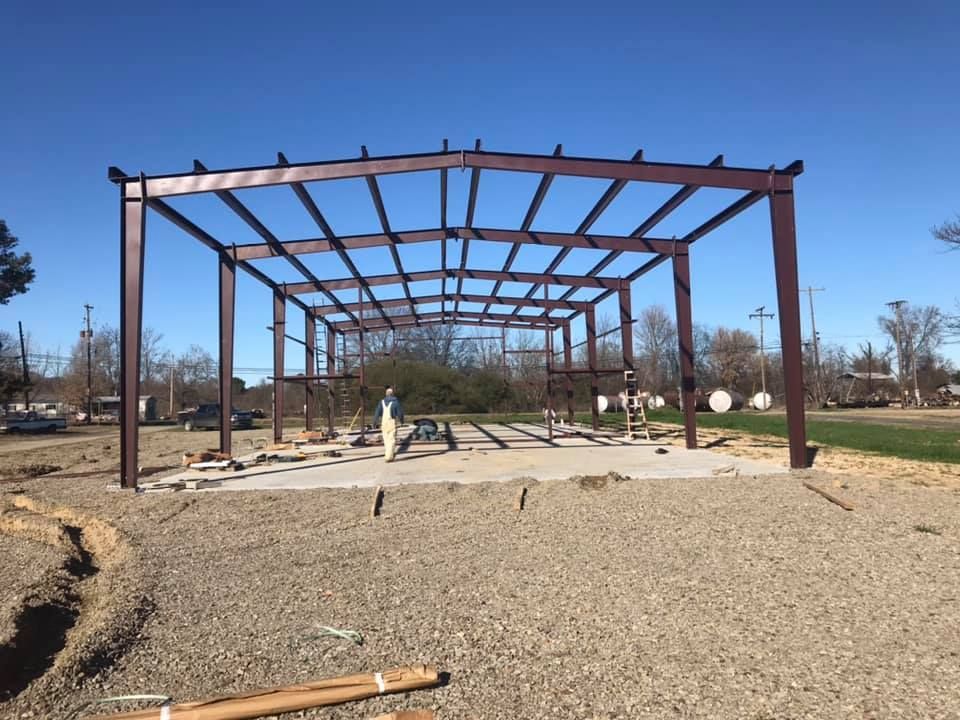 A large metal structure is being built in a gravel area.