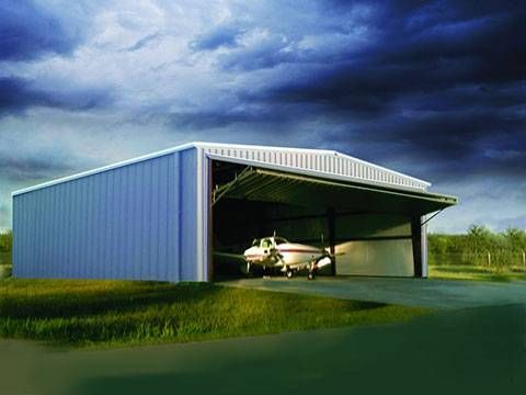 A small plane is parked in a hangar with the door open.