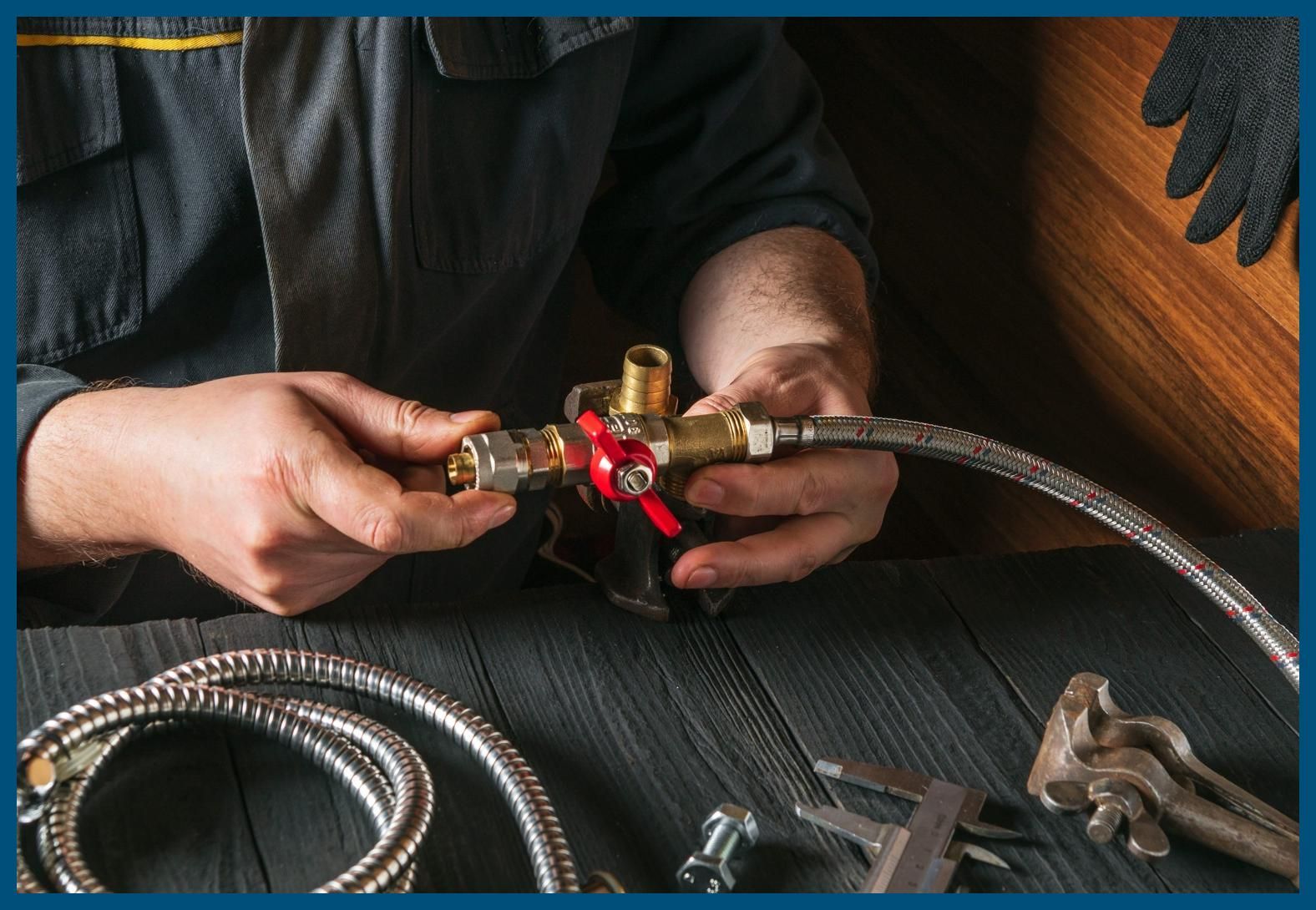 A plumber is working on a hose and valve on a wooden table.