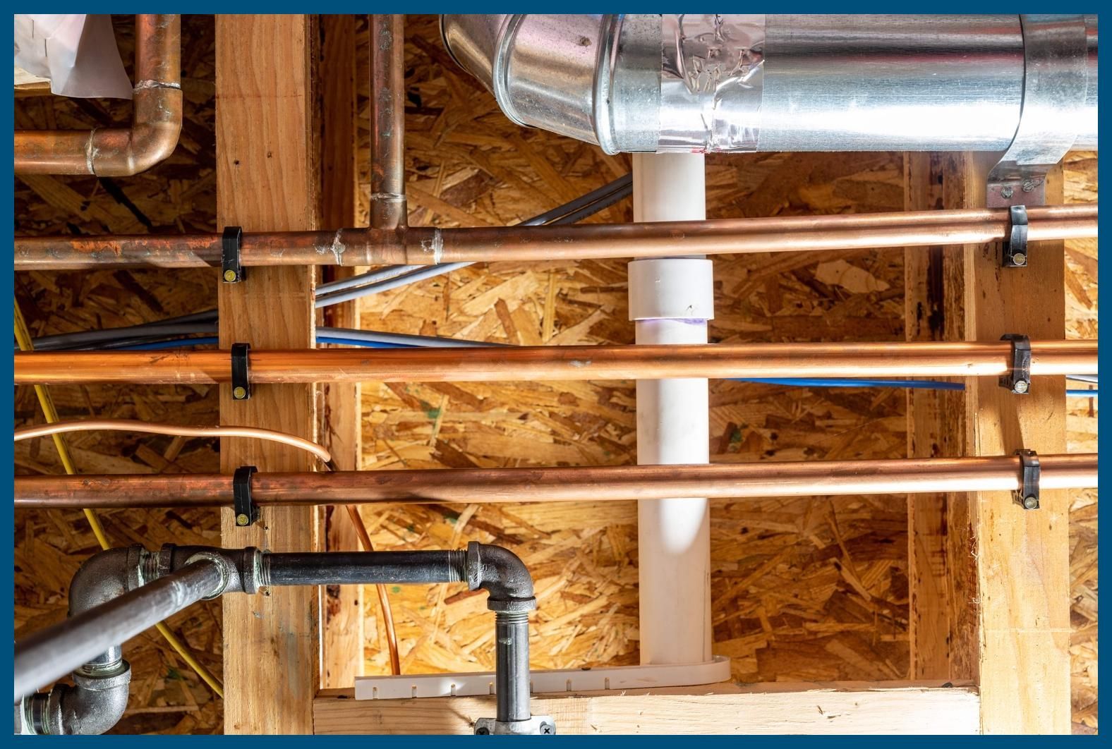 A bunch of pipes are hanging from the ceiling of a house.