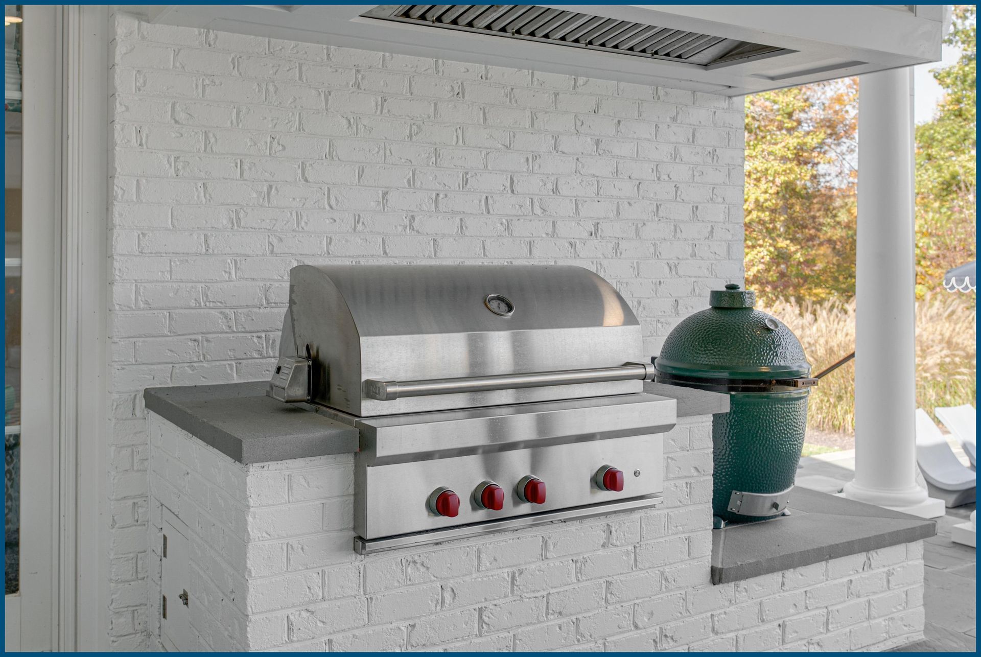 A stainless steel grill is mounted to a white brick wall.