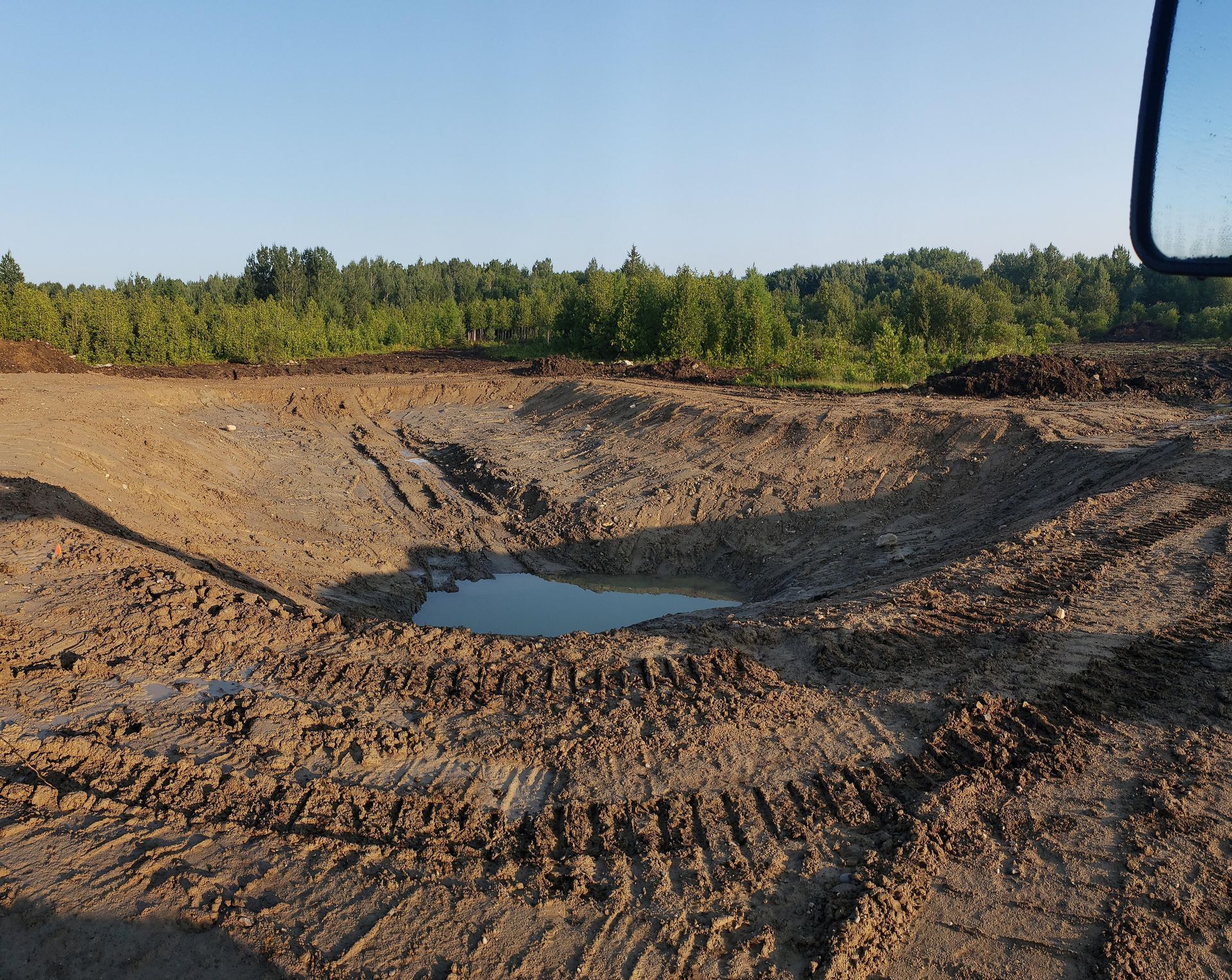 A puddle of water is in the middle of a dirt field