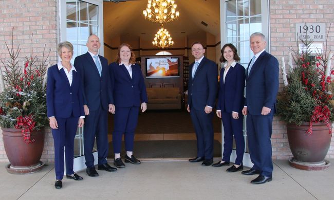The front door of a house with a porch and plants in front of it.
