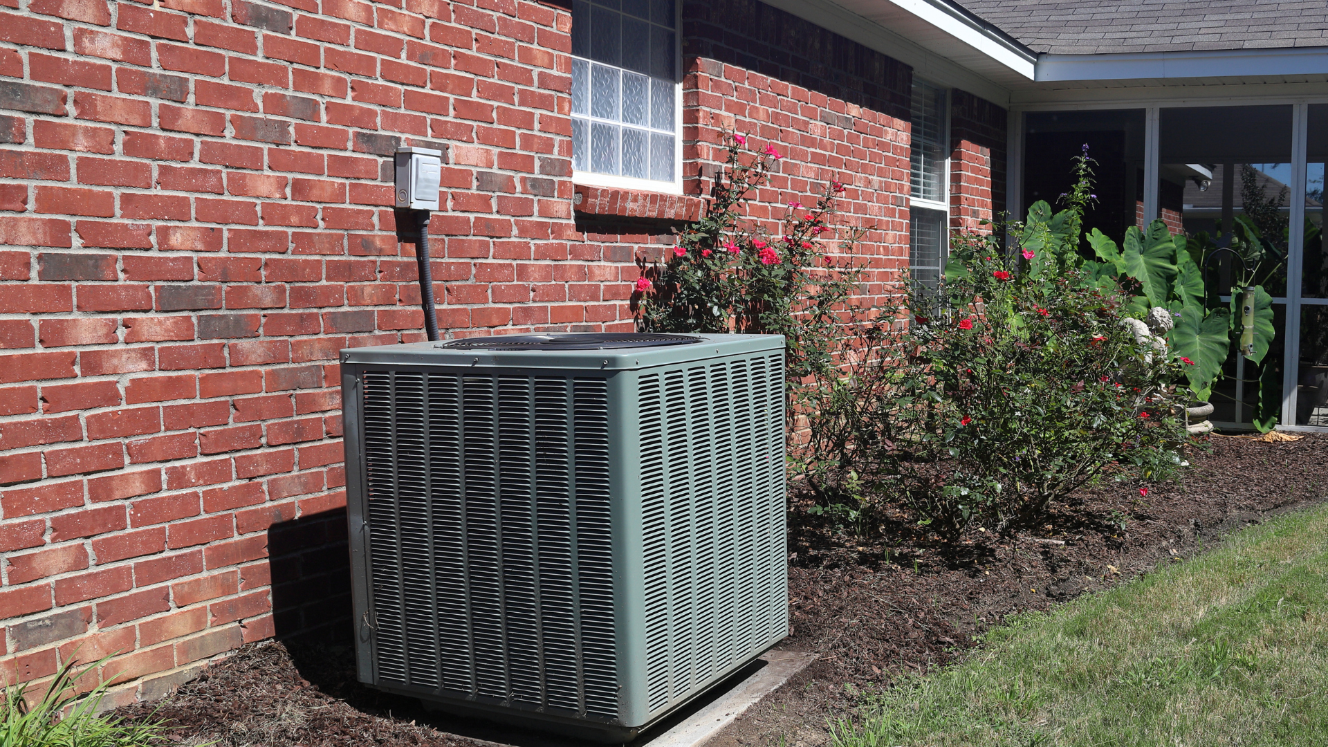 An air conditioner is sitting on the side of a brick house. - Clayton, NC – Parker and Co Heating and Air, LLC