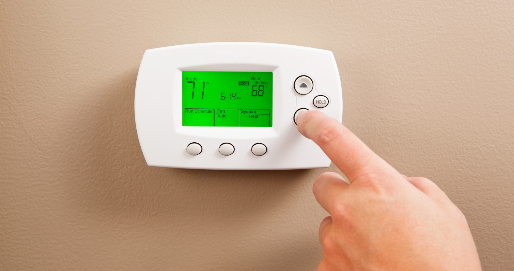 A person is adjusting a thermostat with their finger. - Clayton, NC – Parker and Co Heating and Air, LLC