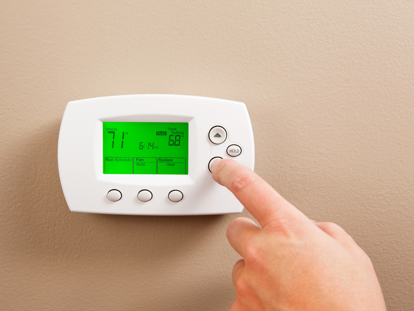 A person is adjusting a thermostat with their finger. - Clayton, NC – Parker and Co Heating and Air, LLC