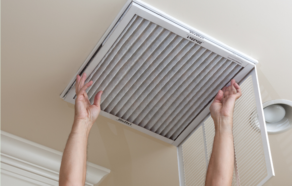 A person is changing a filter on a ceiling vent. - Clayton, NC – Parker and Co Heating and Air, LLC