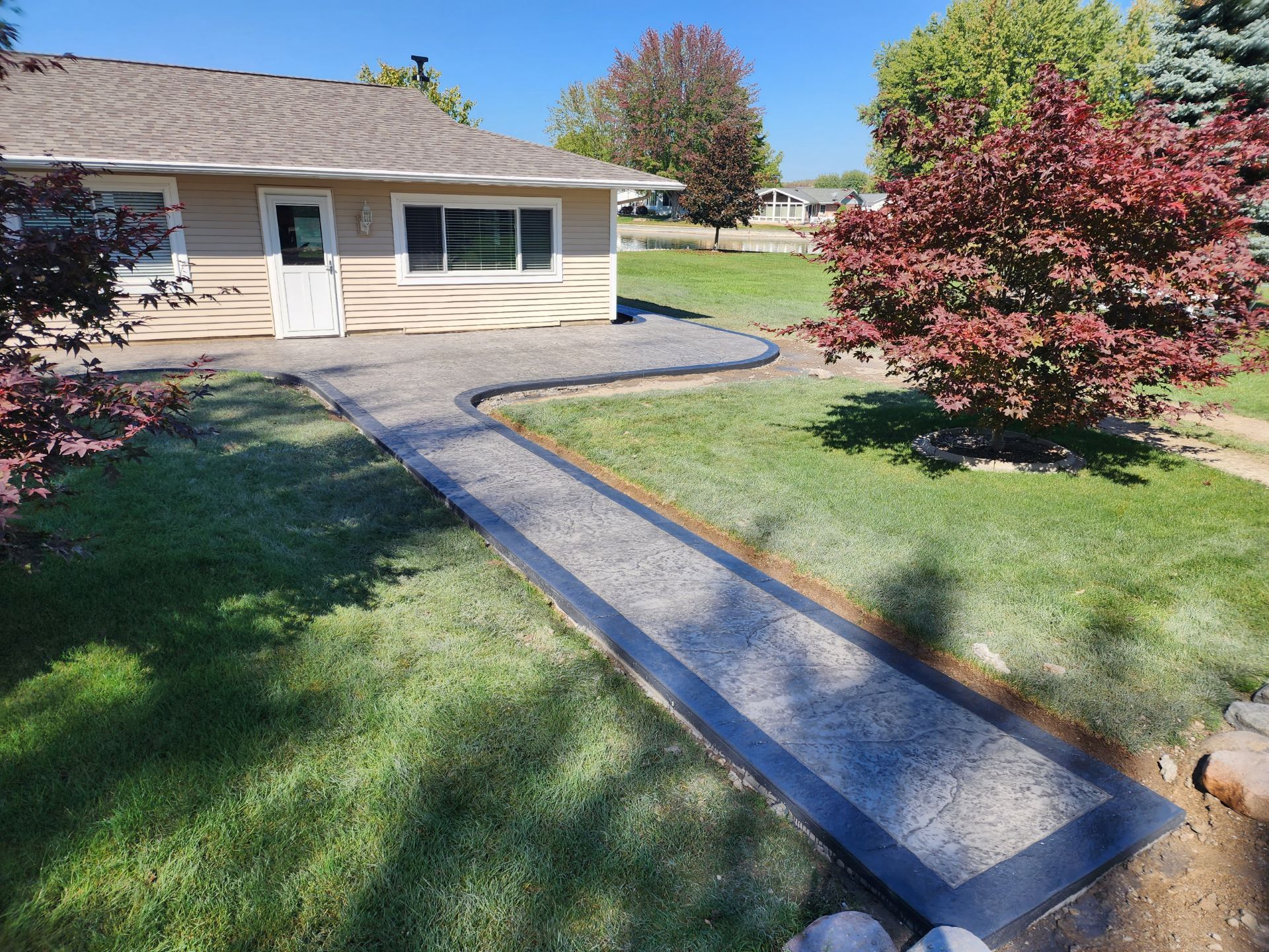A house with a walkway leading to it and a tree in front of it.